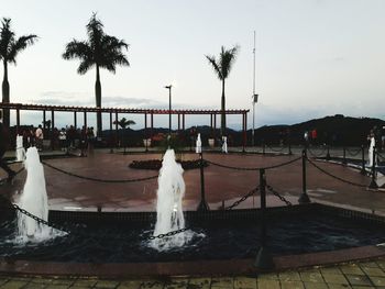 People standing by swimming pool against sky at sunset