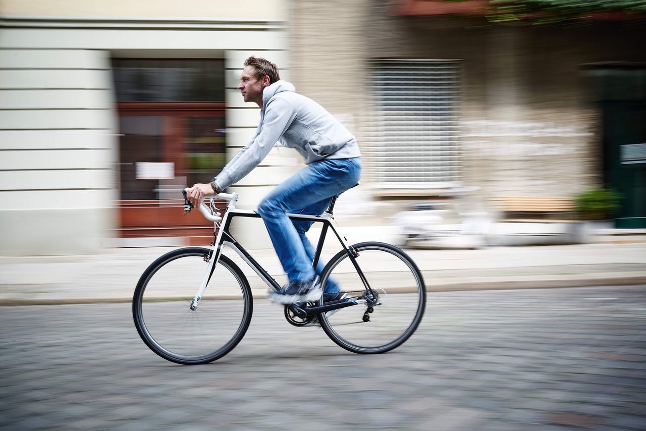 bicycle, full length, transportation, mode of transport, riding, building exterior, lifestyles, land vehicle, side view, street, architecture, built structure, on the move, leisure activity, motion, blurred motion, casual clothing, road