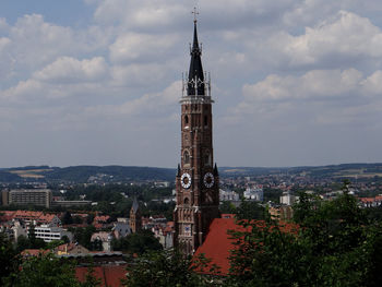 Clock tower in city against cloudy sky