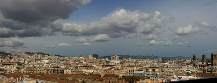 View of cityscape against cloudy sky