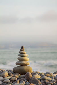 Stack of stones at beach against sky