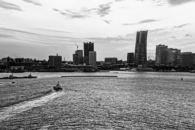 Sea by buildings in city against sky