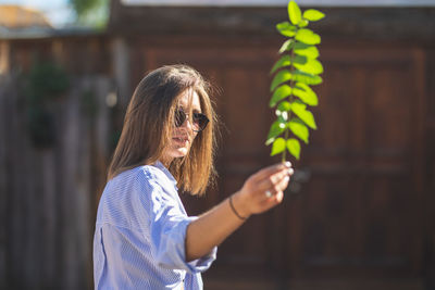 Young woman holding twig during sunny day