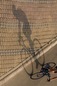 High angle view of bicycle shadow on brick wall