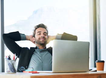 Portrait of businessman using laptop while sitting on table