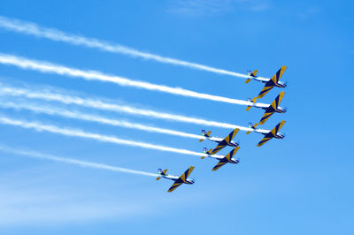 Low angle view of airshow against blue sky