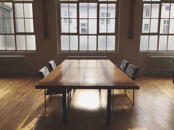 Empty table and chairs on hardwood floor in meeting room