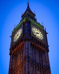 Low angle view of big ben against blue sky in city at dusk