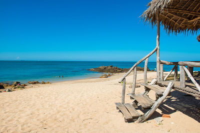 Chairs on beach against clear blue sky