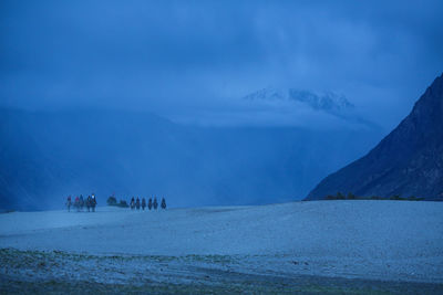 People on mountain by lake against sky
