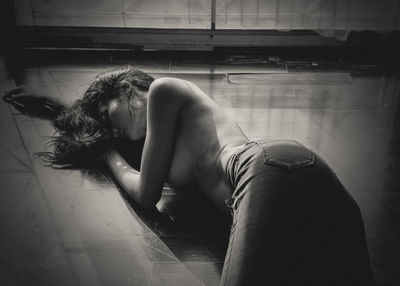 High angle view of shirtless young woman lying on floor at home