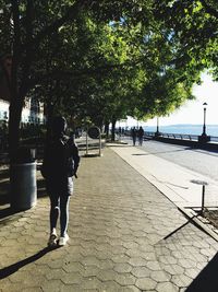 Rear view of people walking on footpath in city