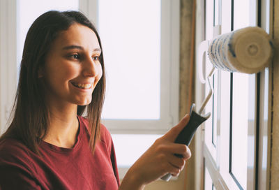 Portrait of smiling young woman holding mobile phone