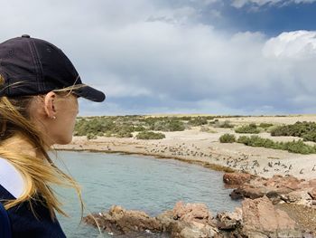 Side view of young woman in sea against sky