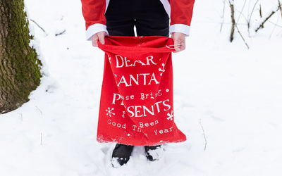 A man dressed as santa claus is holding a large red bag with gifts for children