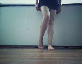 Low section of woman standing on hardwood floor at home