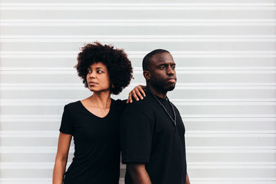 Portrait of young couple standing against wall