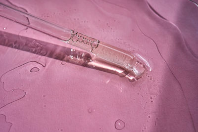 Dropper with serum or cosmetic oil on a pink background.