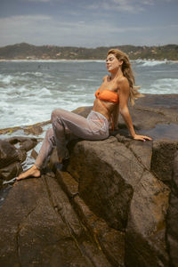 Young woman sitting on rock at beach