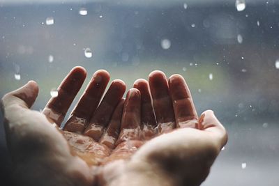 Cropped image of woman with hands cupped in rain