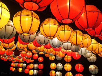 Low angle view of illuminated lanterns hanging against sky at night