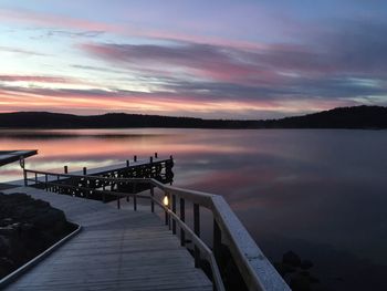 Pier over lake against sky at sunset