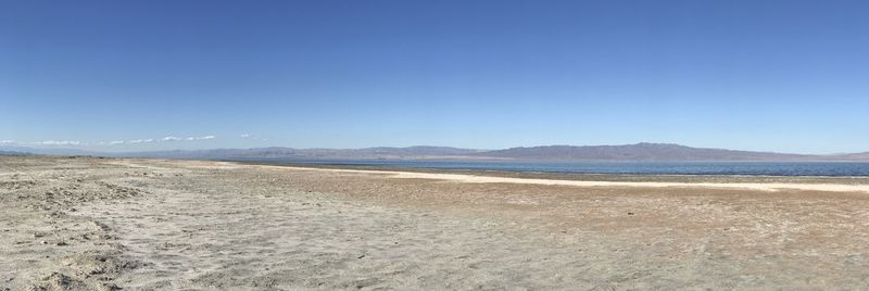 Scenic view of beach against clear blue sky