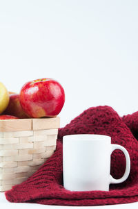 Close-up of strawberries in basket on table against white background