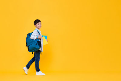 Portrait of young man standing against yellow background