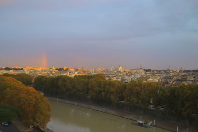 Scenic view of river by buildings against sky during sunset