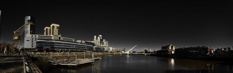 River by illuminated buildings against sky at night