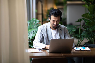 Young man using phone while sitting on table