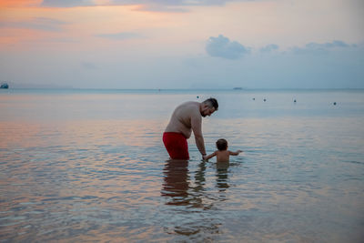 Rear view of man standing at beach against sky