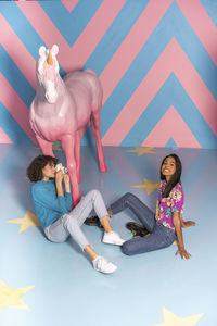 Young woman taking a picture of her friend at an indoor theme park with a unicorn figure