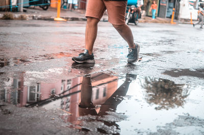 Low section of man standing on wet street