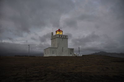 Low angle view of lighthouse by building against sky