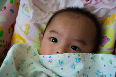 Portrait of cute baby girl lying on bed