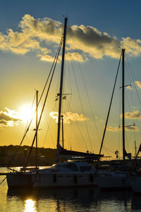 Boats moored at harbor during sunset