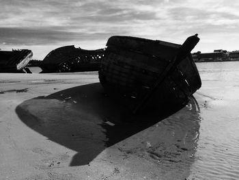Abandoned boat on beach against sky