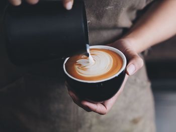 Midsection of person preparing coffee at cafe