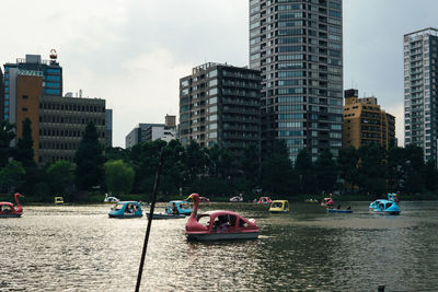 Boats in city by buildings against sky