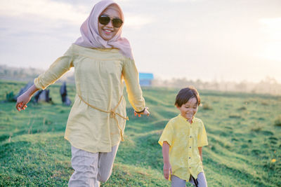 Full length of siblings walking on field