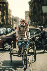 Rear view of man riding bicycles on street