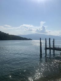 Wooden posts in sea against sky