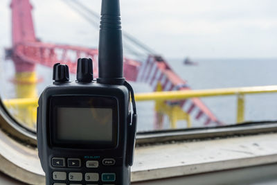 Walkie-talkie on a glass window of a bridge of a construction work barge at offshore oil field 