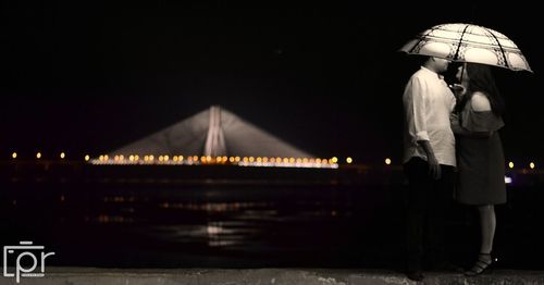 Rear view of man standing on bridge at night