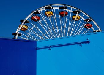 Low angle view of ferris wheel against blue sky