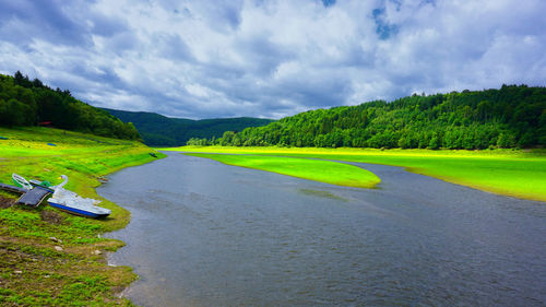 Scenic view of river amidst green landscape against sky