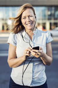 Portrait of happy businesswoman using mobile phone outdoors