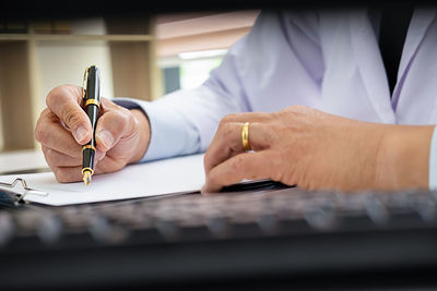 Midsection of man holding paper on table